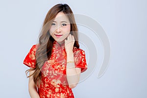 Beautiful portrait happy Chinese New Year young asian woman wear cheongsam smile with gesture congratulation and greeting isolated