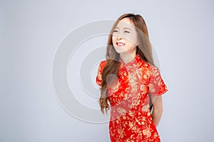 Beautiful portrait happy Chinese New Year young asian woman wear cheongsam smile with gesture congratulation and greeting isolated