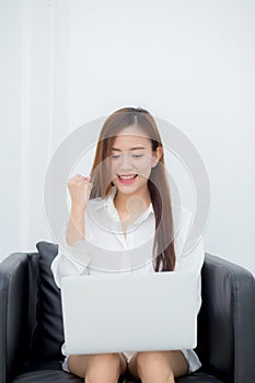 Beautiful of portrait happy young asian woman using laptop work with success on chair in the home