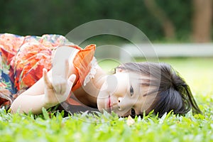 Beautiful portrait little girl asian of a smiling lying on green grass at the park