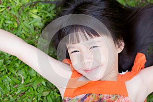 Beautiful portrait little girl asian of a smiling lying on green grass at the park