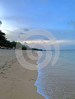 Beautiful portrait picture of a peaceful and empty beach in Bali, Indonesia in the summer during the evening sunset.