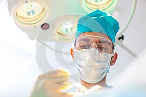 Beautiful portrait of a surgeon doctor at work. The lamp in the background. The surgeon gives injections to the head