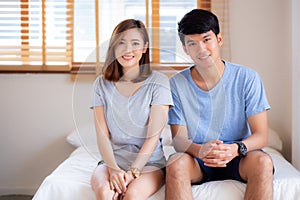 Beautiful portrait young asian couple relax and satisfied together in bedroom at home, family sitting on bed