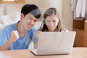 Beautiful portrait young asian couple working laptop with smile and happy sitting in bedroom