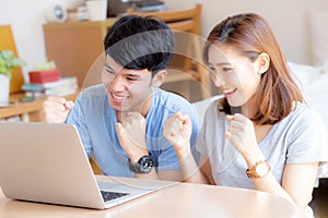 Beautiful portrait young asian couple working laptop with smile and happy sitting in bedroom