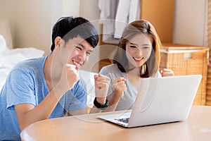 Beautiful portrait young asian couple working laptop with smile and happy sitting in bedroom