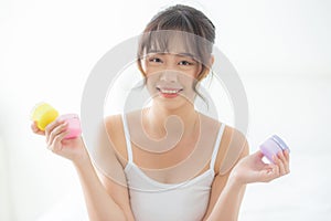 Beautiful portrait young asian woman attractive holding jars of cream and lotion skin for face fresh and soft at the room