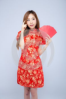 Beautiful portrait young asian woman cheongsam dress smiling and think idea holding red envelope on white background