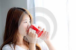 Beautiful of portrait young asian woman with drink acup of coffee standing curtain window background