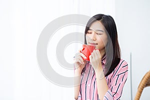 Beautiful of portrait young asian woman with drink a cup of coffee standing curtain window background