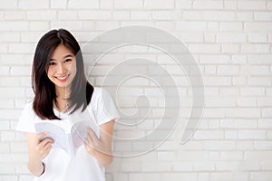 Beautiful of portrait young asian woman happiness relax standing reading book on concrete cement white background