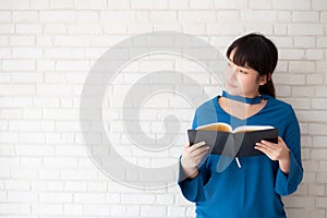 Beautiful of portrait young asian woman happiness relax standing reading book on concrete cement white background.