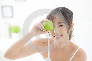 Beautiful portrait young asian woman holding and eating green apple fruit in the bedroom at home.