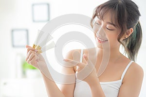 Beautiful portrait young asian woman holding and pointing presenting cream or lotion product