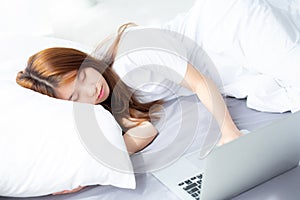 Beautiful of portrait young asian woman with laptop lying down in bedroom.