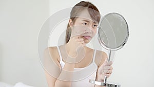 Beautiful portrait young asian woman looking the mirror and touch face is a acne, zit treatment