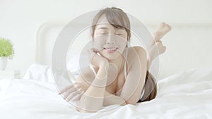 Beautiful portrait young asian woman lying and smile while wake up with sunrise at good morning, girl with happy at bedroom