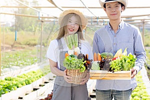 Beautiful portrait young asian woman and man harvest and picking up fresh organic vegetable garden in basket