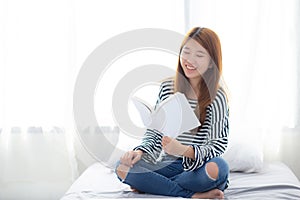 Beautiful of portrait young asian woman relax sitting reading book on bedroom at home