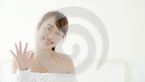 Beautiful portrait young asian woman sitting on bed with smile and happy at bedroom, girl with confident gesture bye