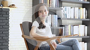 Beautiful portrait young asian woman sitting on chair with smile and happy at living room