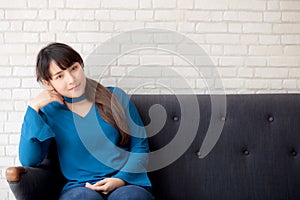 Beautiful portrait young asian woman sitting and smiling happy and looking at camera on sofa with casual at living room