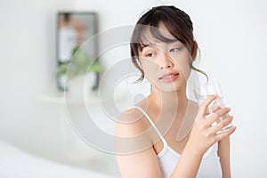 Beautiful portrait young asian woman smile and drinking water glass with fresh and pure for diet