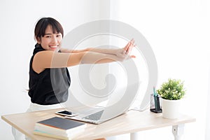 Beautiful portrait young asian woman stretching muscle arms after working with laptop