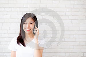 Beautiful of portrait young asian woman talk smart phone and smile standing on cement brick background