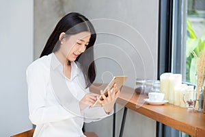 Beautiful portrait young asian woman using tablet computer in the coffee shop.