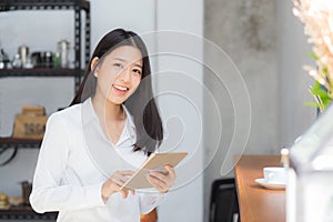 Beautiful portrait young asian woman using tablet computer in the coffee shop.