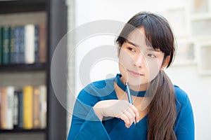 Beautiful portrait young asian woman writer smiling thinking idea and writing on notebook or diary with happy