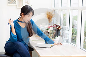 Beautiful portrait young asian woman writer smiling thinking idea and writing on notebook or diary with happy