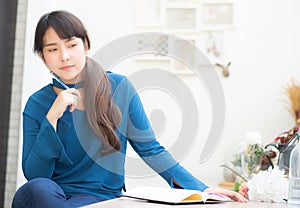 Beautiful portrait young asian woman writer smiling thinking idea and writing on notebook or diary with happy