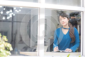 Beautiful portrait young asian woman writer writing on notebook or diary with happy