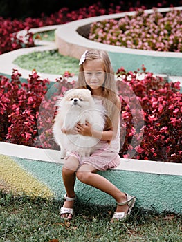 Beautiful portrait of a young girl hugging her dog. A kid with a dog on a park background. Cute home pets. Life concept.