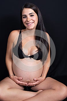 Beautiful Portrait of young pregnant woman underwear sit on black floor background