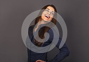Beautiful positive business happy woman in blue shirt looking back with toothy smile on empty copy space grey background. Closeup