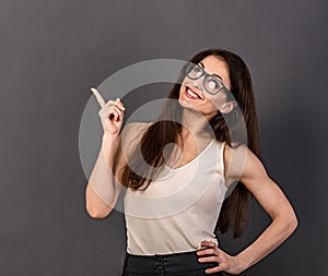 Beautiful positive business happy woman in eyewear in white t- shirt showing up and  demonstrate idea sign by fingers above on