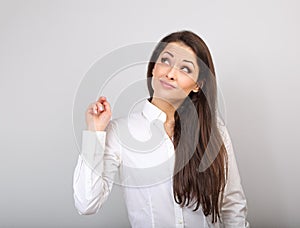 Beautiful positive business happy woman in white shirt showing idea sign by finger and looking up on blue background