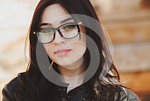 Beautiful positive fashionable stylish modern brunette girl in trendy glasses looking at camera