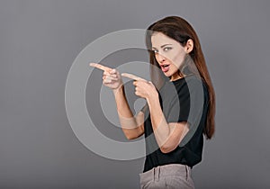 Beautiful positive grimacing humor business happy woman in black t-shirt showing the fingers of two hands on empty copy space grey