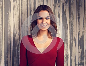 Beautiful positive toothy smiling woman and looking happy in casual red shirt and short curly hair on empty copy space background