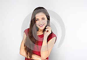 Beautiful positive young happy woman with hand under the face thinking and looking in casual red shirt and long hair on blue
