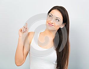 Beautiful positive young happy woman with hand under the face thinking and looking up in casual white t-shirt and long hair on