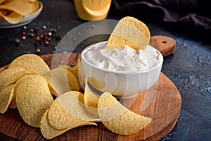 Beautiful potato chips and white sauce bowl. On a dark blue abstract background