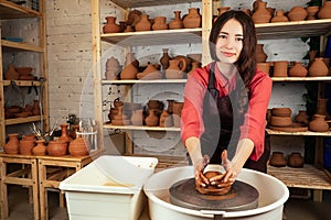 Beautiful potter girl molds from clay pot in mastre. a woman works with clay on a potter`s wheel. clay pot in the hands