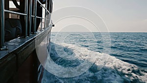 Beautiful POV shot of cruise yacht boat side sailing fast in open sea, cutting shining blue waves on clear sunny day.