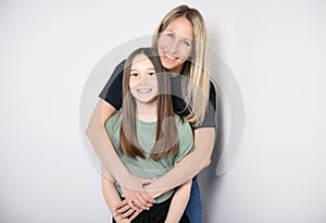 Beautiful pre teen girl with mother on studio white background